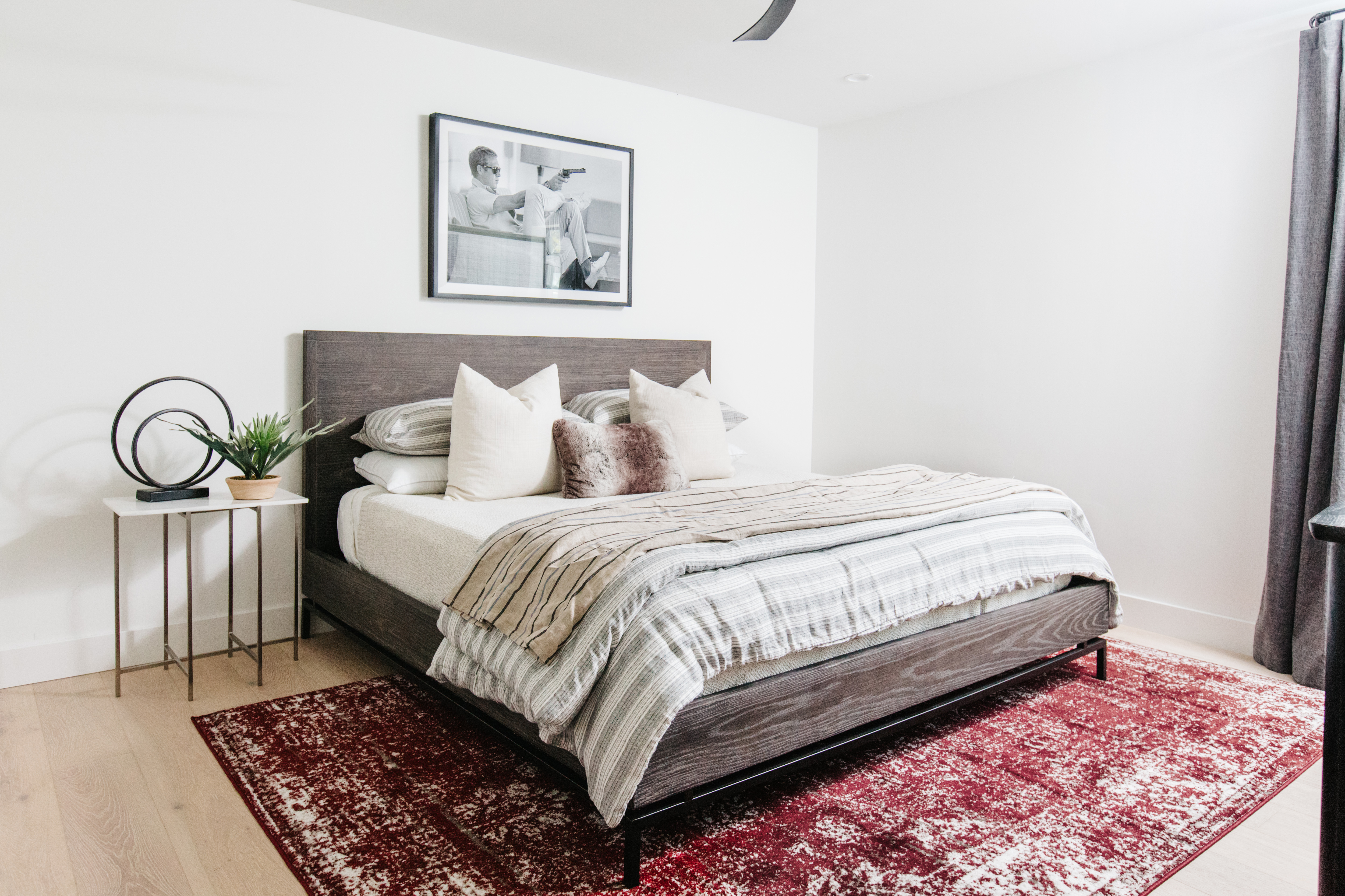 guest bedroom with modern shaped gray wood bed red rug black and white artwork